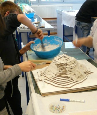 After gluing the cardboard sheets, the relief is coated with plaster.